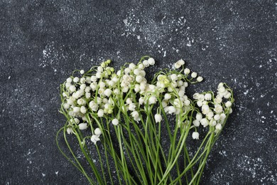 Photo of Beautiful lily-of-the-valley flowers on black textured background, flat lay
