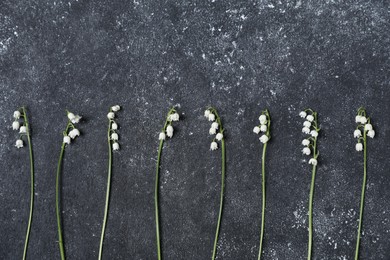 Photo of Beautiful lily-of-the-valley flowers on black textured background, flat lay. Space for text