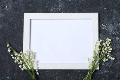 Photo of Beautiful lily-of-the-valley flowers and blank frame on black textured background, flat lay. Space for text