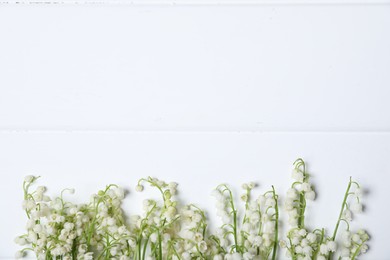 Photo of Beautiful lily-of-the-valley flowers on white wooden background, flat lay. Space for text