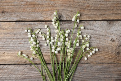 Photo of Beautiful lily-of-the-valley flowers on wooden background, flat lay