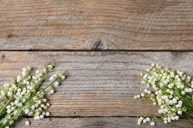 Photo of Beautiful lily-of-the-valley flowers on wooden background, flat lay. Space for text