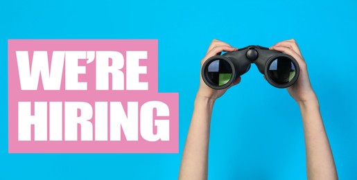 Image of We Are Hiring. Woman with binoculars on light blue background, closeup. Recruitment, human resources concept