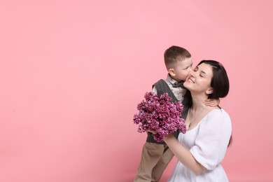Photo of Mother and her son with bouquet of lilac flowers on pink background, space for text
