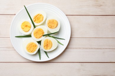 Photo of Boiled eggs and green onions on wooden table, top view. Space for text