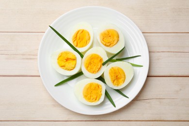 Photo of Boiled eggs and green onions on wooden table, top view