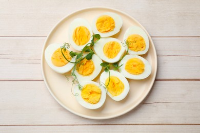 Photo of Boiled eggs and microgreens on wooden table, top view