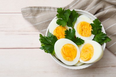 Photo of Boiled eggs and parsley in bowl on wooden table, top view. Space for text