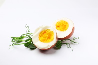 Photo of Halves of hard boiled egg and microgreens on white background