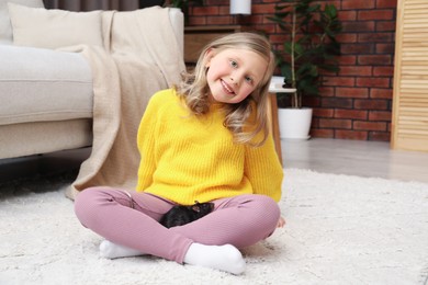 Photo of Little girl with cute black rat on floor at home