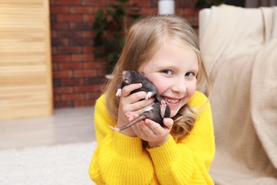 Photo of Little girl with cute black rat at home