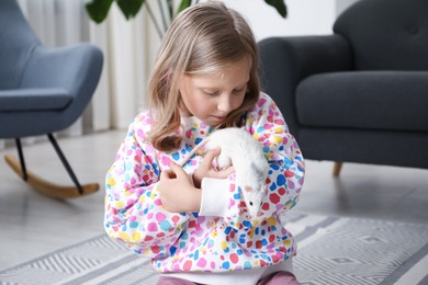 Photo of Little girl with cute white rat at home