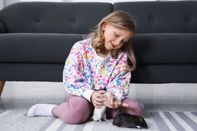 Photo of Little girl with cute rats on floor at home