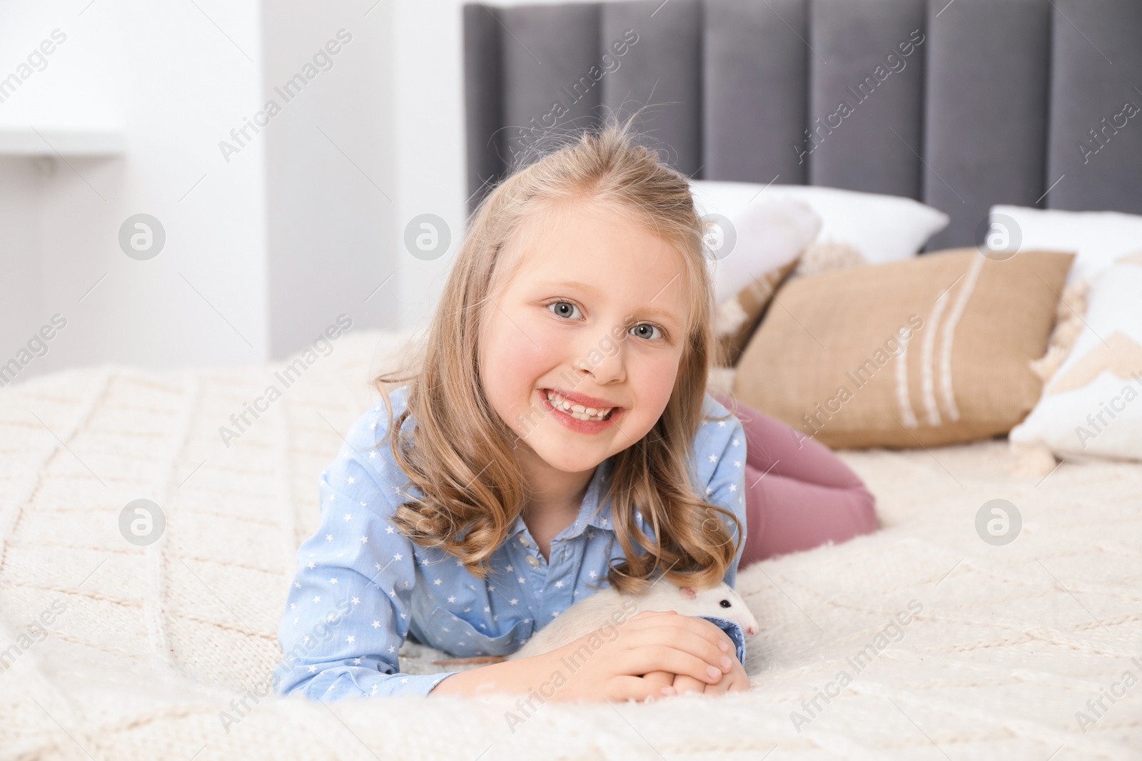 Little girl with cute white rat on bed at home Photo of Little girl with cute white rat on bed at home