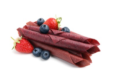 Photo of Tasty fruit leather rolls, strawberries and blueberries isolated on white