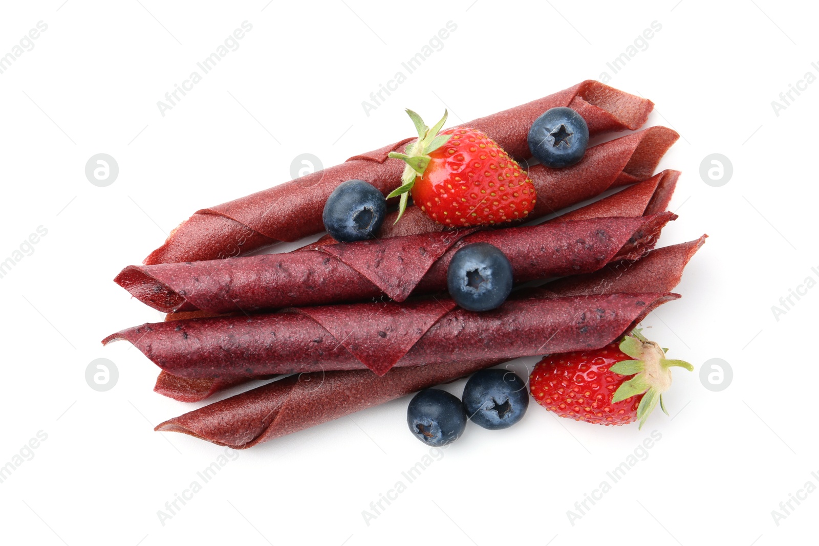 Tasty fruit leather rolls, strawberries and blueberries isolated on white, top view Photo of Tasty fruit leather rolls, strawberries and blueberries isolated on white, top view