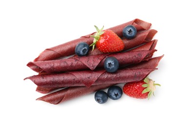 Photo of Tasty fruit leather rolls, strawberries and blueberries isolated on white, top view