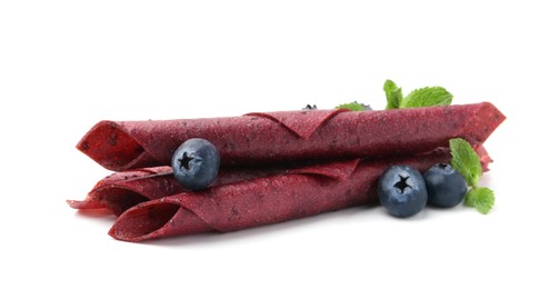 Photo of Tasty fruit leather rolls, blueberries and mint isolated on white