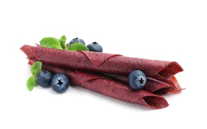 Photo of Tasty fruit leather rolls, blueberries and mint isolated on white