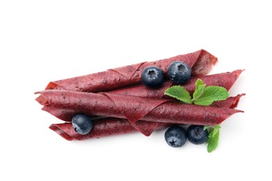Photo of Tasty fruit leather rolls, blueberries and mint isolated on white, top view
