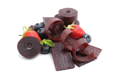 Photo of Tasty fruit leather rolls, strawberries and blueberries isolated on white