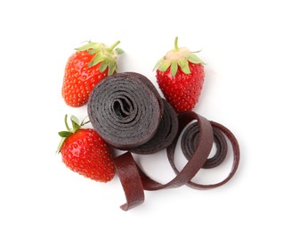 Photo of Tasty fruit leather rolls and strawberries isolated on white, top view