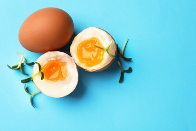 Photo of Soft boiled eggs with microgreens on light blue background, top view