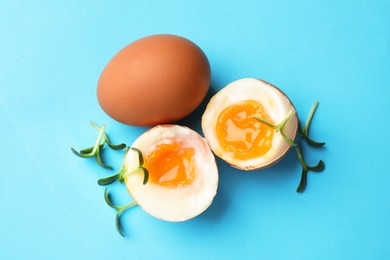 Photo of Soft boiled eggs with microgreens on light blue background, top view