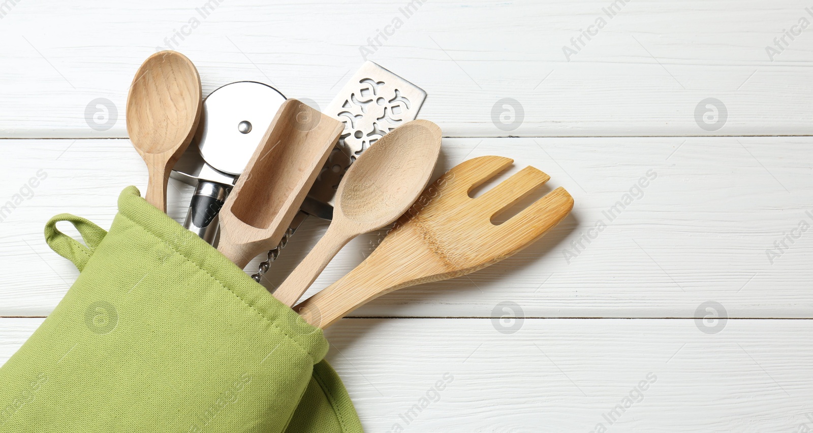Different kitchen utensils in oven mitten on white wooden table, top view. Space for text Photo of Different kitchen utensils in oven mitten on white wooden table, top view. Space for text