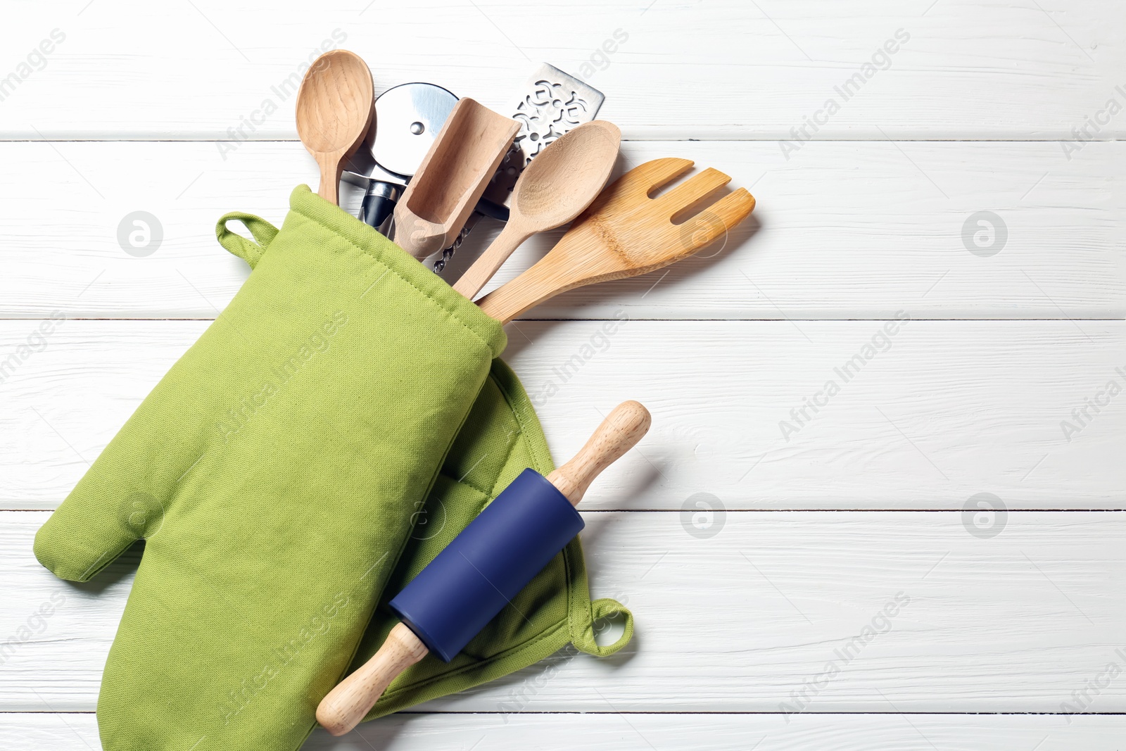 Different kitchen utensils in oven mitten on white wooden table, top view. Space for text Photo of Different kitchen utensils in oven mitten on white wooden table, top view. Space for text