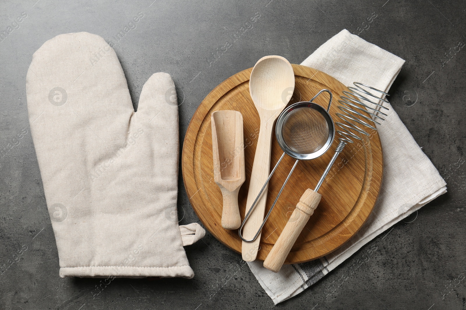 Different kitchen utensils and oven mitten on grey table, flat lay Photo of Different kitchen utensils and oven mitten on grey table, flat lay