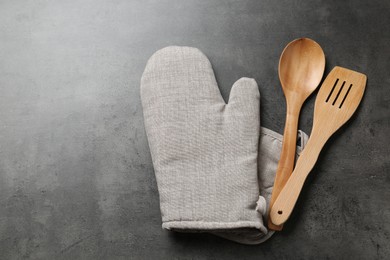 Photo of Spoon, spatula and oven mitten on grey table, flat lay. Space for text