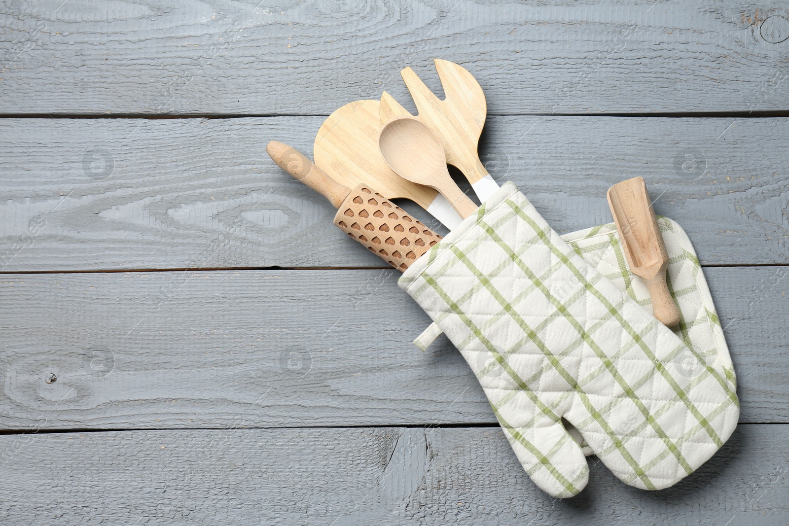 Different kitchen utensils in oven mitten on light grey wooden table, top view. Space for text Photo of Different kitchen utensils in oven mitten on light grey wooden table, top view. Space for text