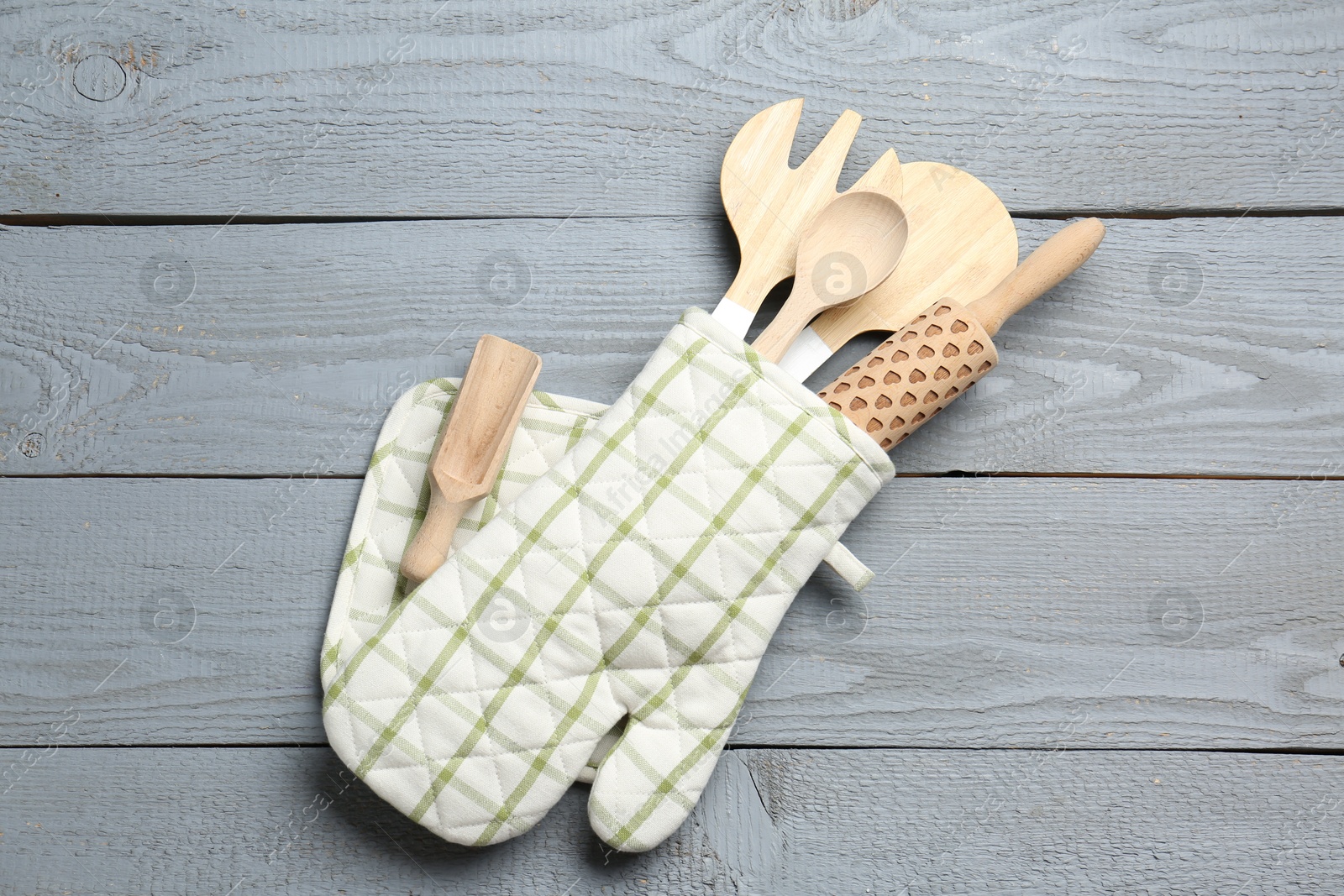 Different kitchen utensils in oven mitten on light grey wooden table, top view Photo of Different kitchen utensils in oven mitten on light grey wooden table, top view
