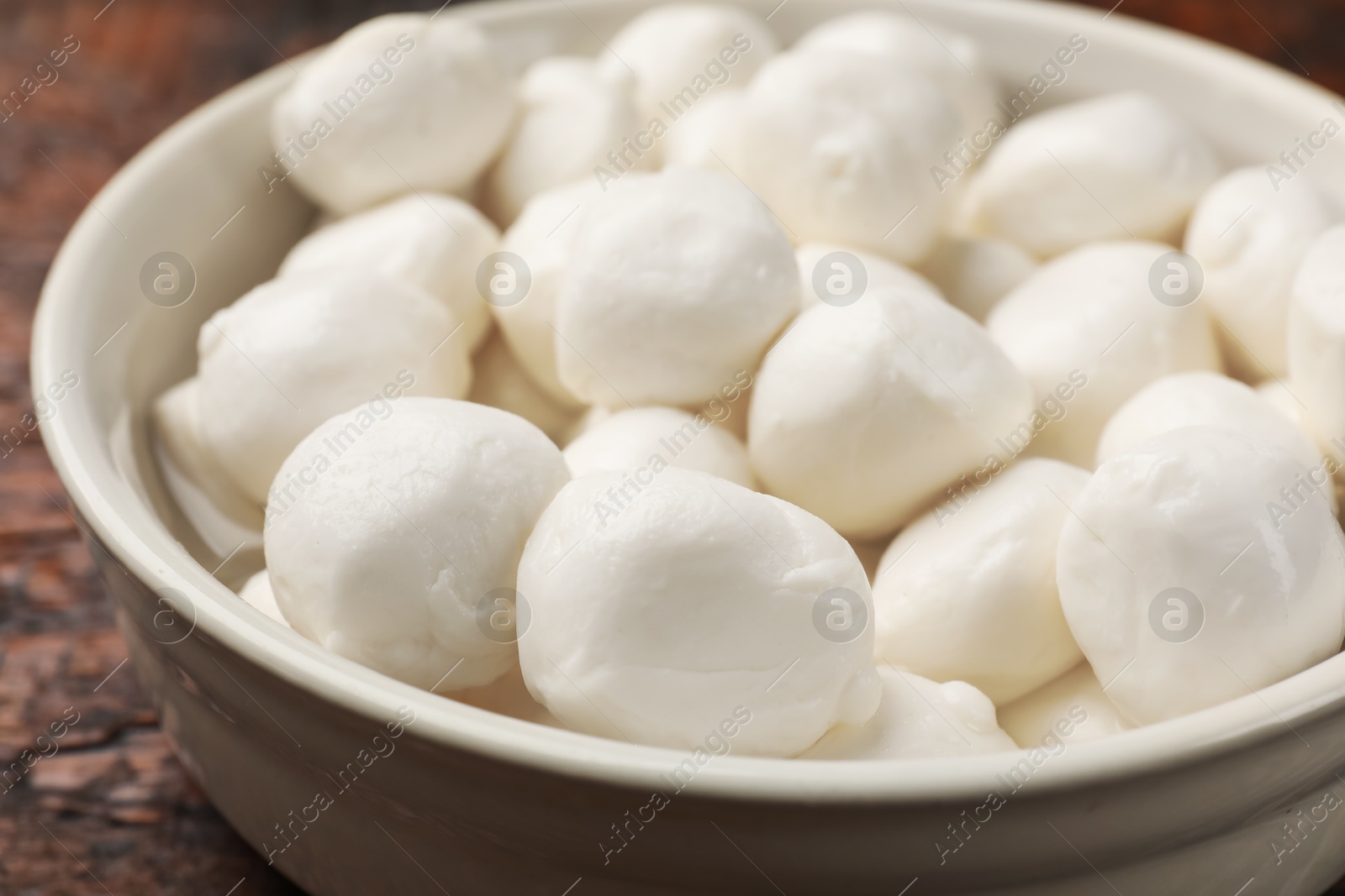 Tasty mozzarella cheese balls in bowl on wooden table, closeup Photo of Tasty mozzarella cheese balls in bowl on wooden table, closeup