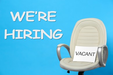 Image of We Are Hiring. Office chair with Vacant sign on light blue background. Recruitment, human resources concept