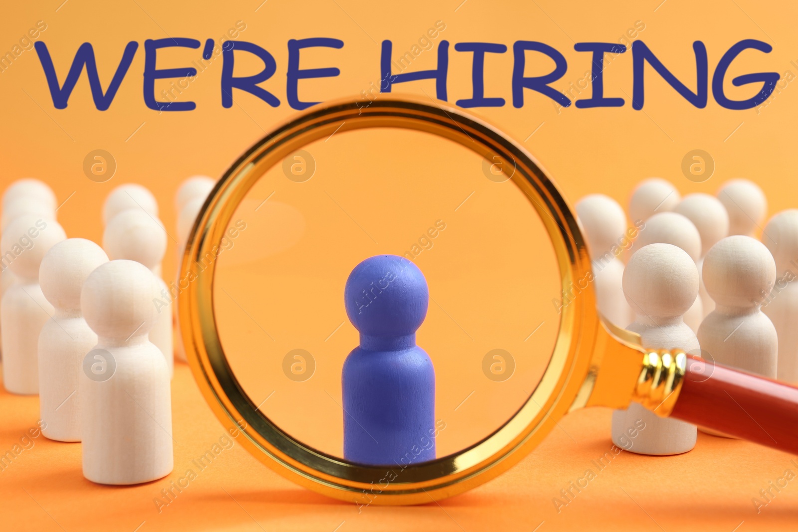 We Are Hiring. Blue figure among wooden ones on orange background, view through magnifying glass. Recruitment, human resources concept Image of We Are Hiring. Blue figure among wooden ones on orange background, view through magnifying glass. Recruitment, human resources concept