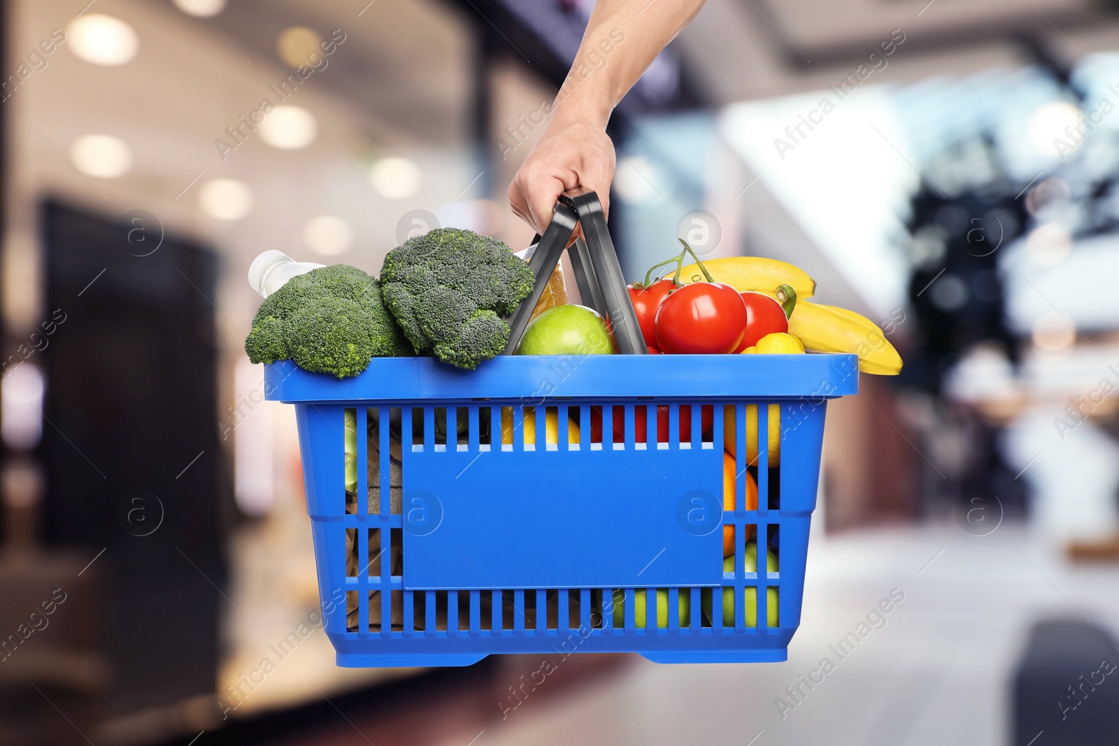 Man holding shopping basket with different food products at supermarket, closeup Image of Man holding shopping basket with different food products at supermarket, closeup