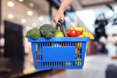 Image of Man holding shopping basket with different food products at supermarket, closeup