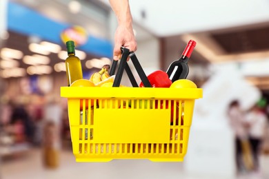 Image of Man holding shopping basket with different food products at supermarket, closeup