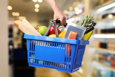 Image of Man holding shopping basket with different food products at supermarket, closeup