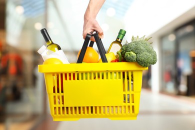 Image of Man holding shopping basket with different food products at supermarket, closeup