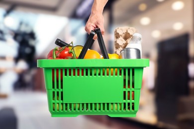 Image of Man holding shopping basket with different food products at supermarket, closeup