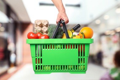 Image of Man holding shopping basket with different food products at supermarket, closeup