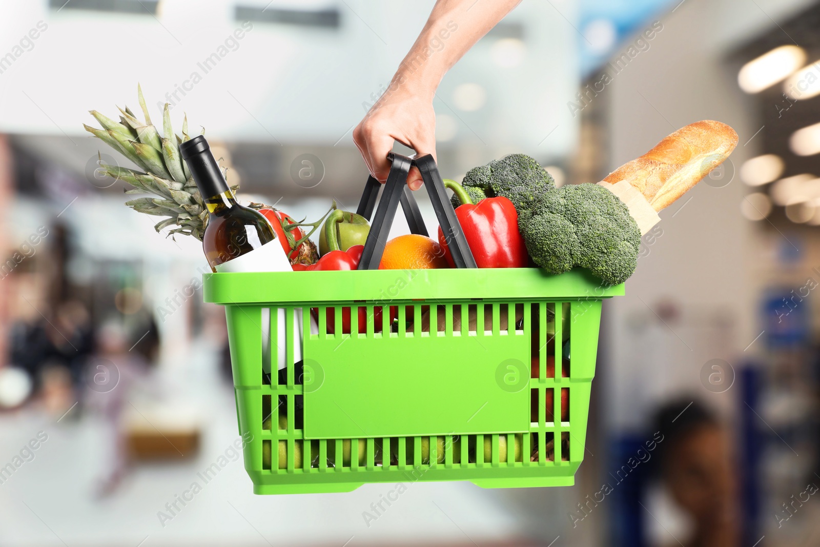Man holding shopping basket with different food products at supermarket, closeup Image of Man holding shopping basket with different food products at supermarket, closeup