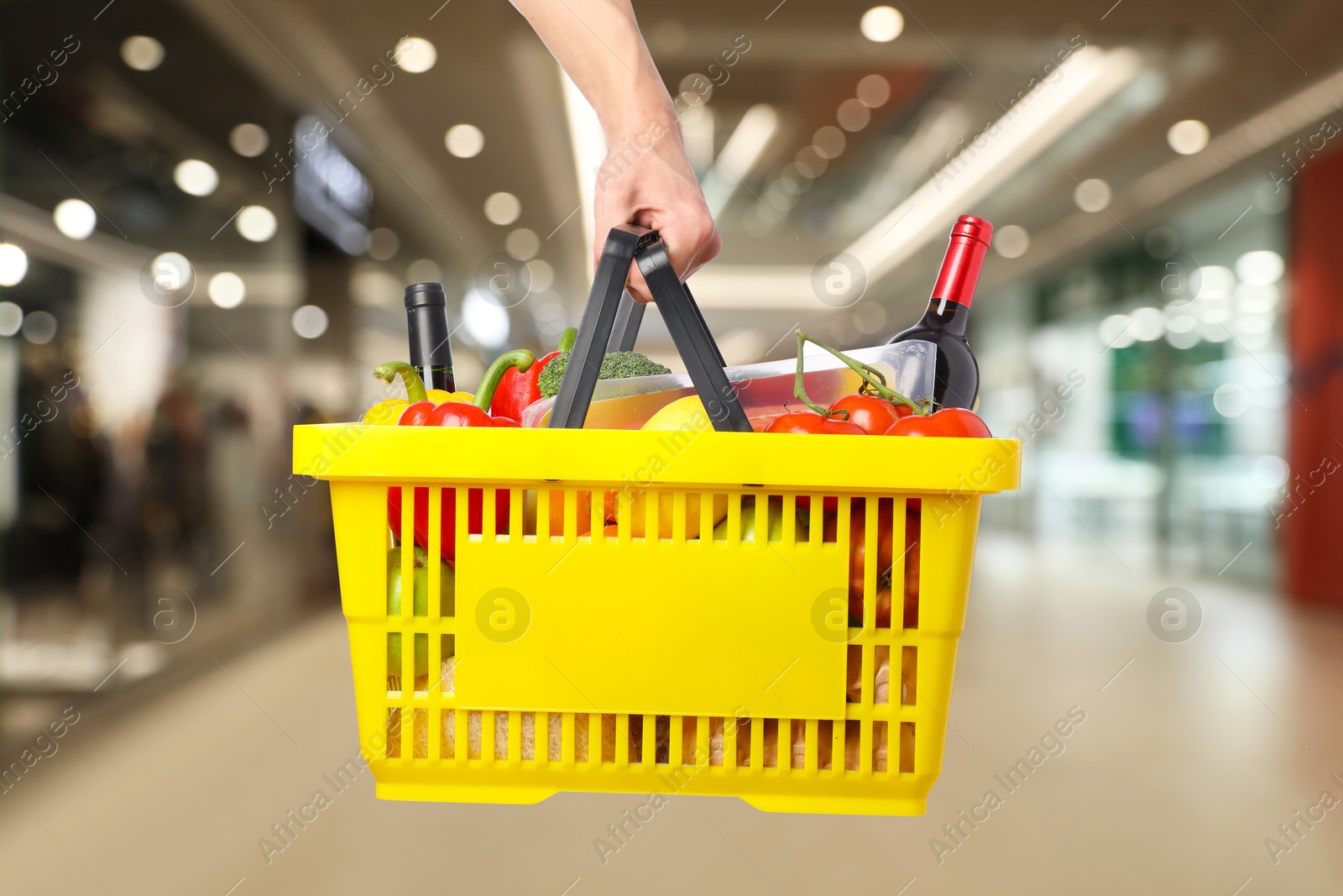 Man holding shopping basket with different food products at supermarket, closeup Image of Man holding shopping basket with different food products at supermarket, closeup