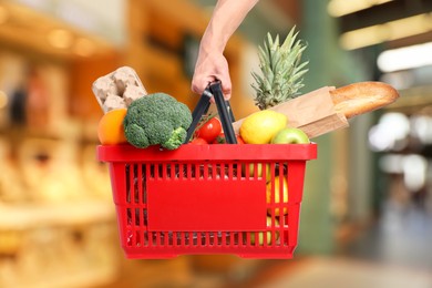 Image of Man holding shopping basket with different food products at supermarket, closeup