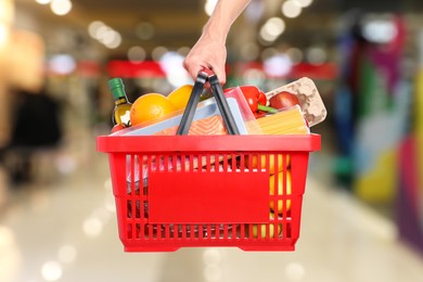 Image of Man holding shopping basket with different food products at supermarket, closeup