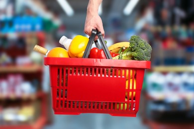 Image of Man holding shopping basket with different food products at supermarket, closeup