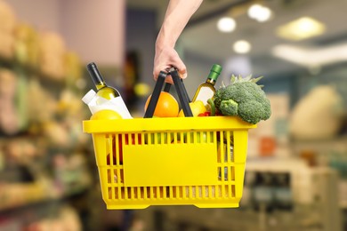 Image of Man holding shopping basket with different food products at supermarket, closeup